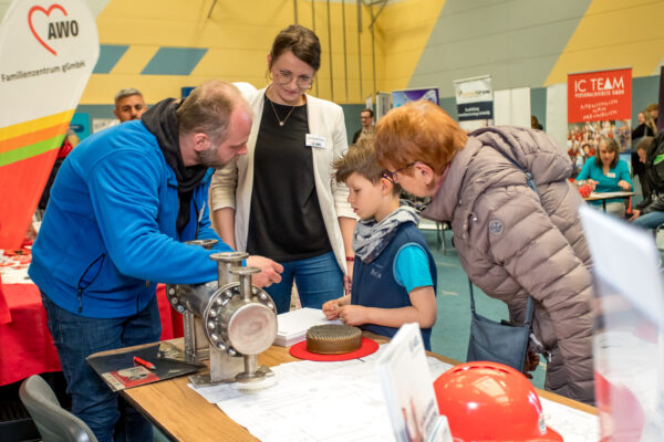 Ein Mitarbeiter der AEL erklärt einem Jungen auf der Messe den Aufbau und die Funktionsweise eines Wärmeübertragers.